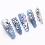 Each nail is adorned with various elements like rhinestones, pearls, snowflakes, and chains, adding a touch of sparkle and sophistication.